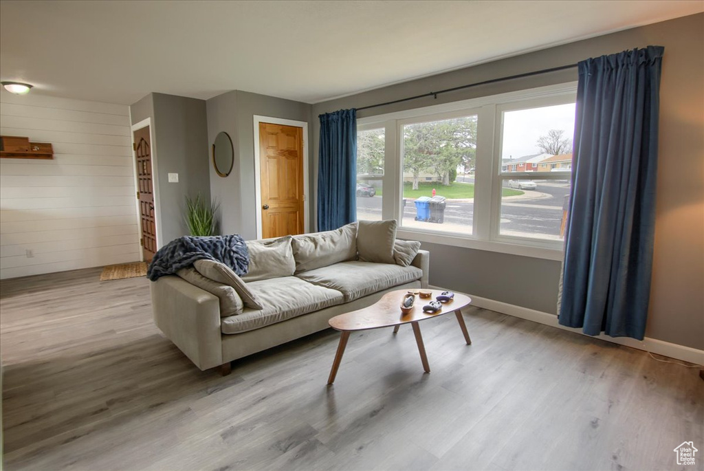 Living room featuring baseboards, wooden walls, and light wood-type flooring