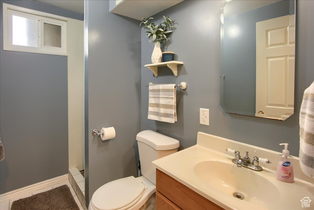 Bathroom with toilet, vanity, tile patterned floors, and baseboards