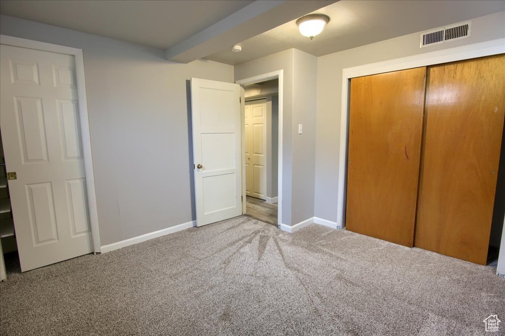 Unfurnished bedroom with carpet floors, a closet, visible vents, and baseboards