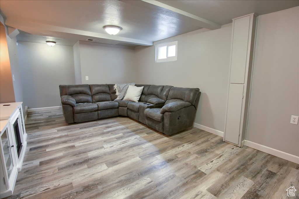 Living room featuring beamed ceiling, light wood-type flooring, visible vents, and baseboards