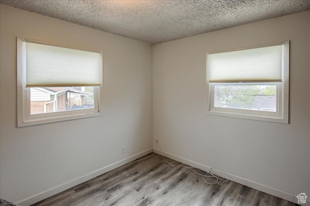 Spare room featuring baseboards, a textured ceiling, and light wood finished floors