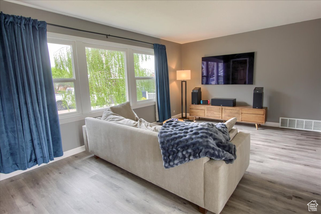 Living room featuring visible vents, plenty of natural light, baseboards, and wood finished floors