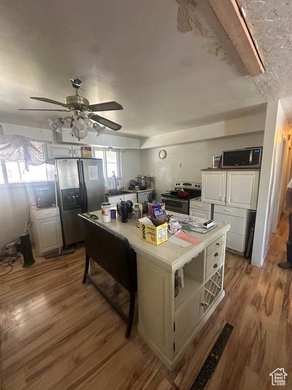 Kitchen featuring white cabinets, a ceiling fan, light wood-style floors, a kitchen island, and appliances with stainless steel finishes