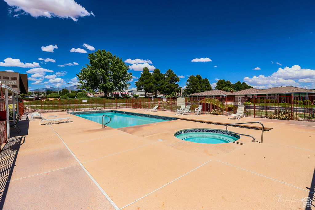 Pool with fence, a patio area, and a community hot tub