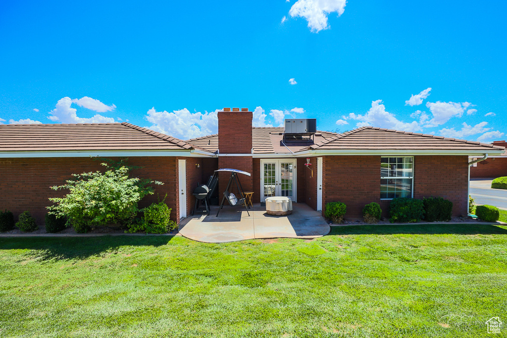 Back of house featuring a yard, cooling unit, a patio area, and a tiled roof