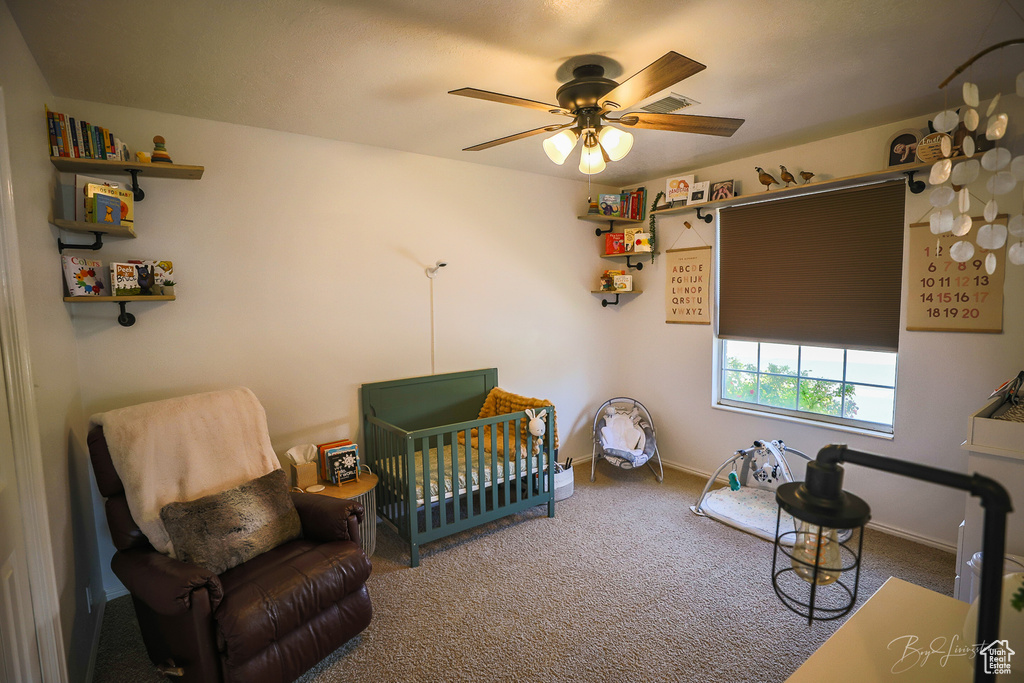 Bedroom with visible vents, baseboards, a ceiling fan, a crib, and carpet floors