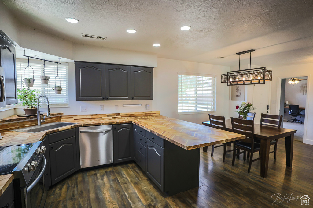 Kitchen with wooden counters, visible vents, a sink, a textured ceiling, and appliances with stainless steel finishes