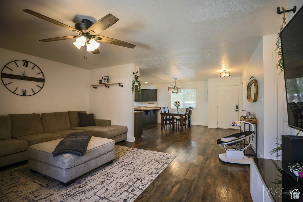 Living area featuring dark wood finished floors, baseboards, and ceiling fan
