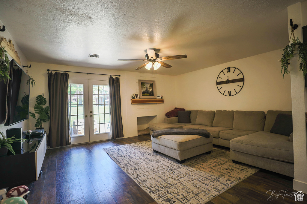Living area featuring dark wood-style floors, visible vents, french doors, a textured ceiling, and ceiling fan
