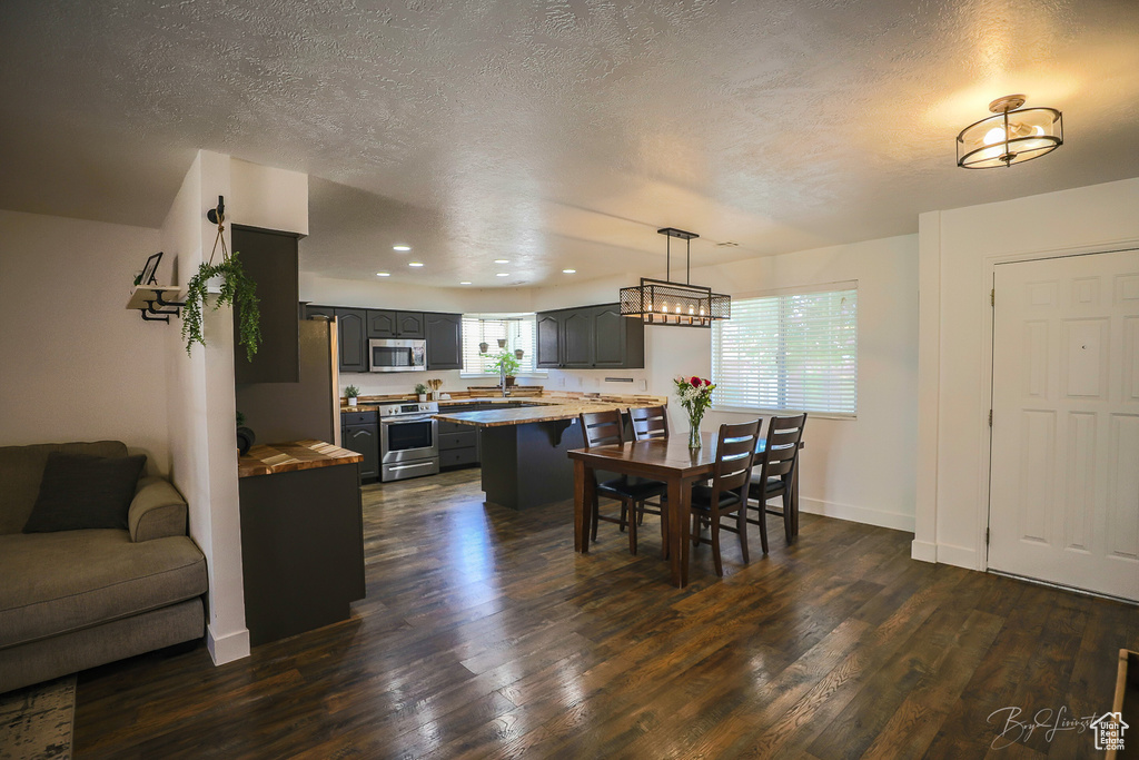 Dining room featuring a textured ceiling, dark wood-style floors, and recessed lighting