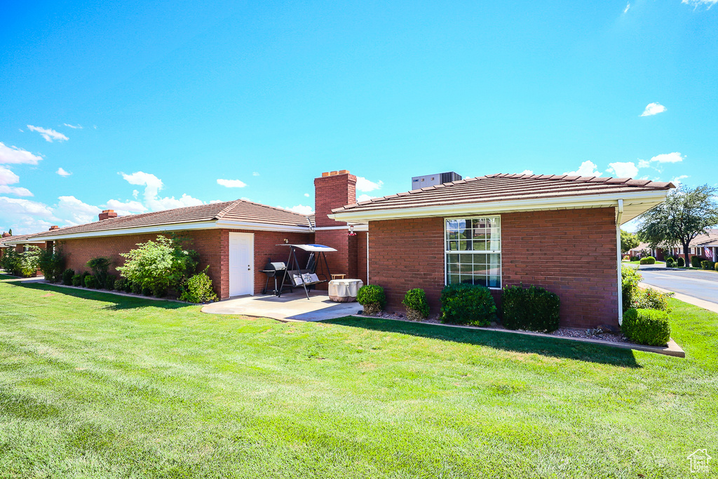 Back of property featuring a tiled roof, a chimney, a yard, and a patio