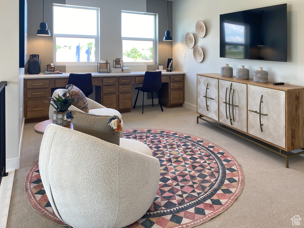 Living room with baseboards, plenty of natural light, light colored carpet, and built in desk