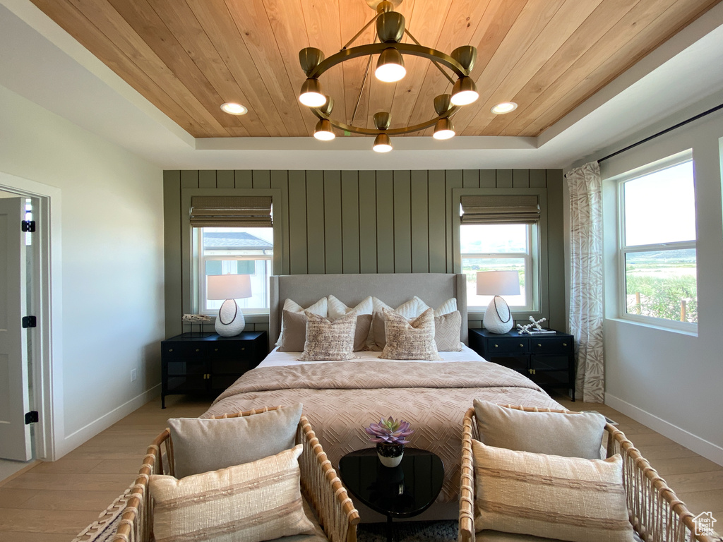 Bedroom with wood ceiling, light wood-style flooring, baseboards, and a tray ceiling