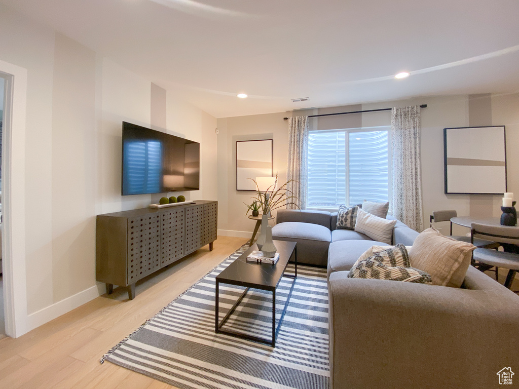 Living room with baseboards, recessed lighting, and light wood-style floors
