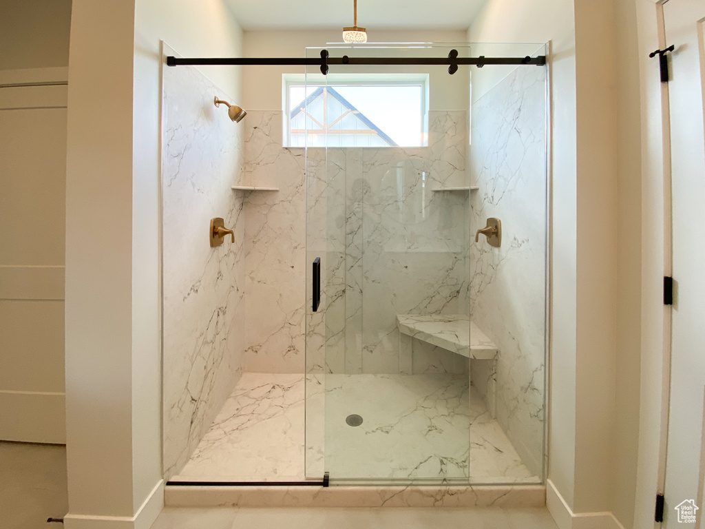 Bathroom featuring baseboards and a marble finish shower