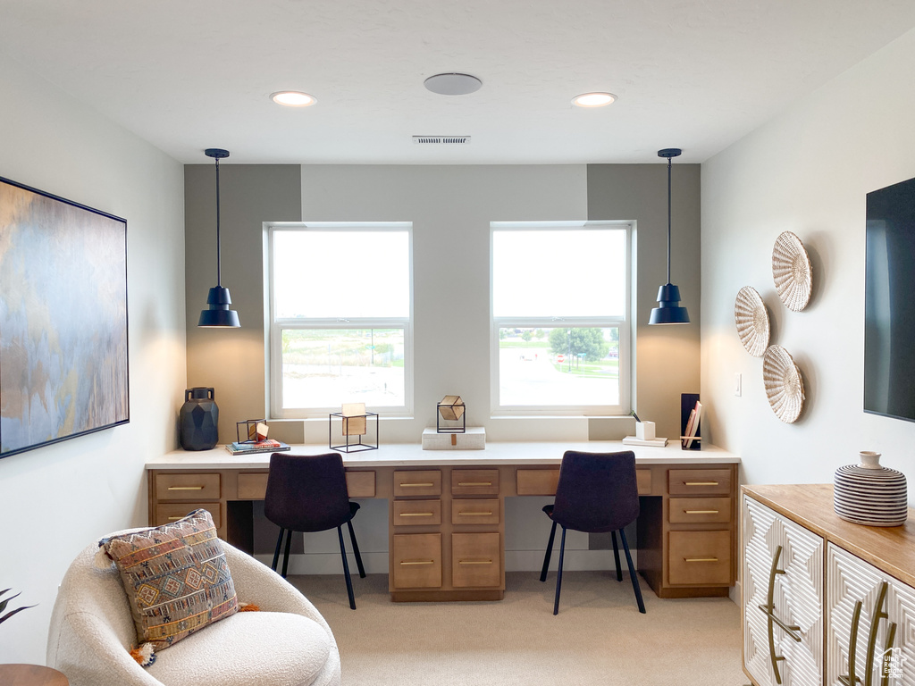 Office area with light colored carpet, a healthy amount of sunlight, visible vents, and built in desk
