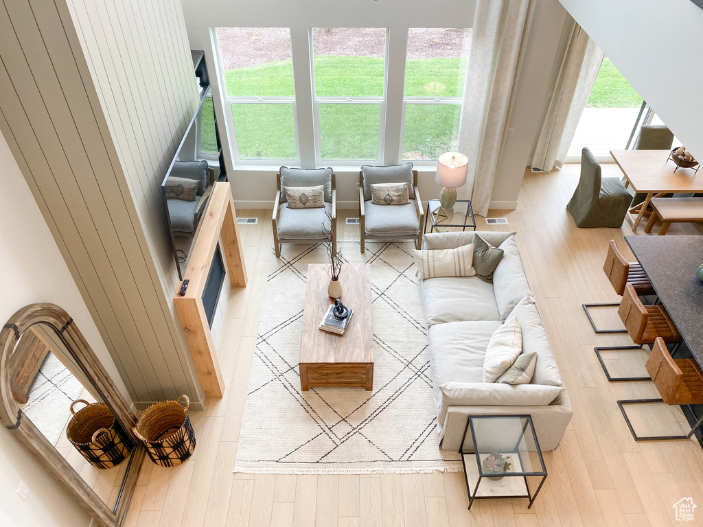 Living room with light wood-type flooring, visible vents, baseboards, and plenty of natural light