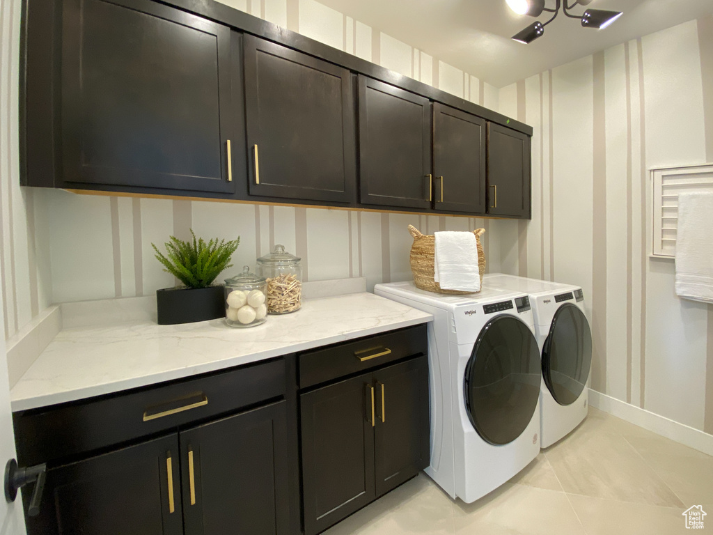 Clothes washing area featuring separate washer and dryer, baseboards, a decorative wall, and cabinet space