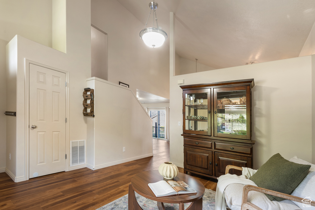 Living room with baseboards, wood finished floors, visible vents, and high vaulted ceiling