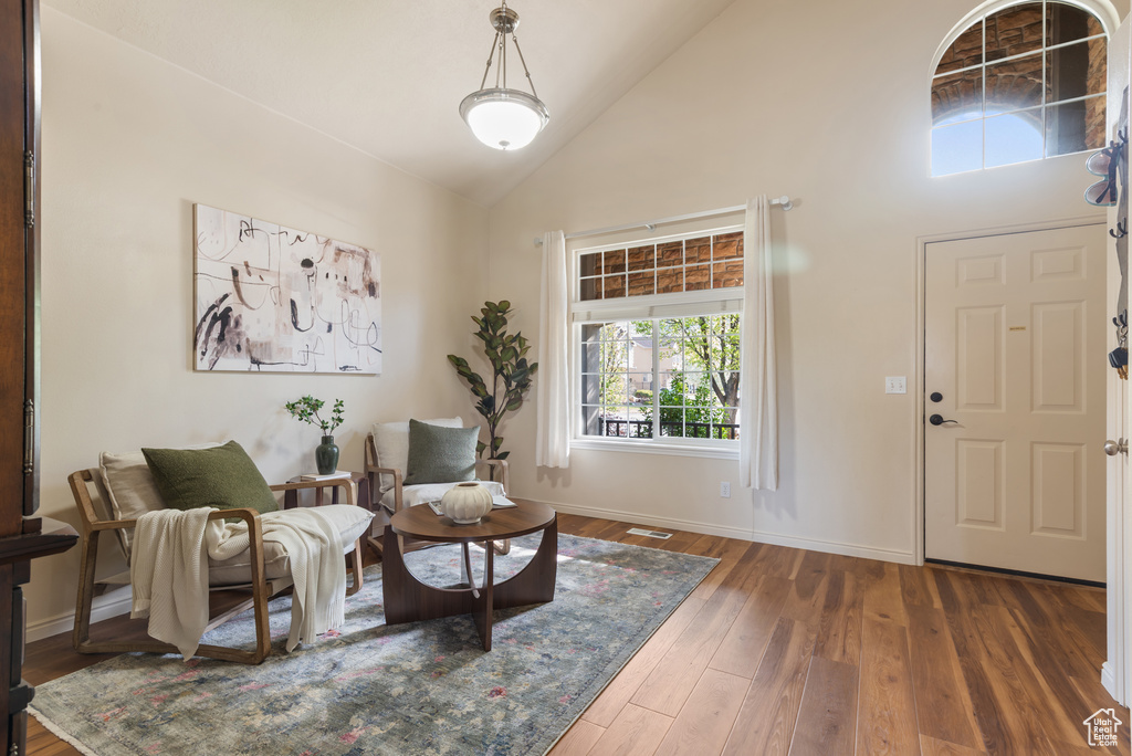 Foyer entrance with high vaulted ceiling, baseboards, a healthy amount of sunlight, and hardwood / wood-style floors