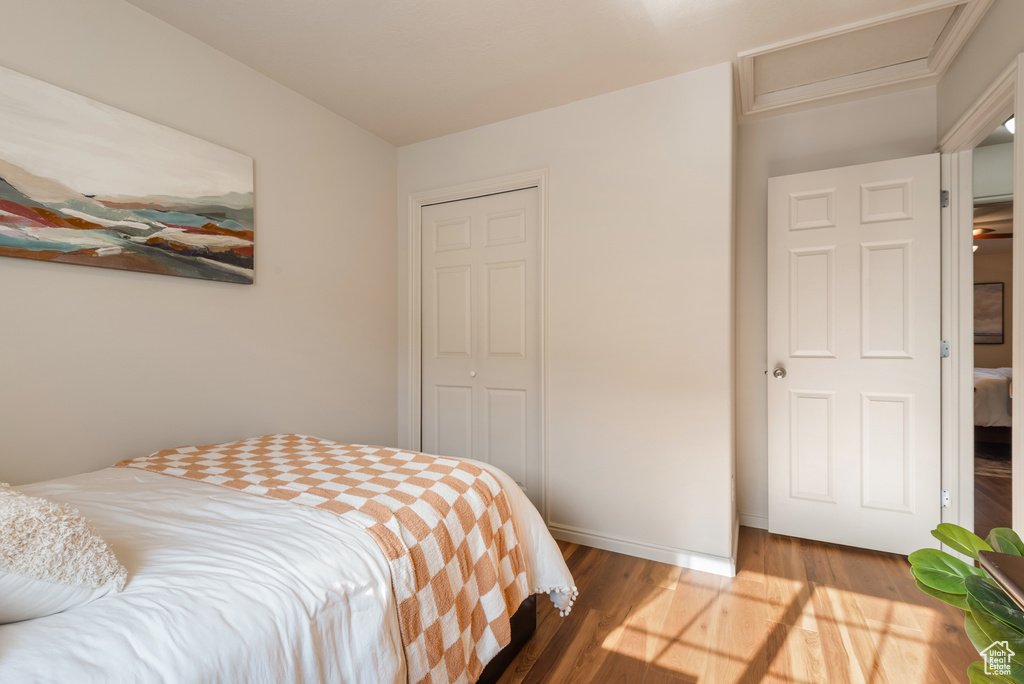 Bedroom with attic access, baseboards, wood finished floors, and a closet