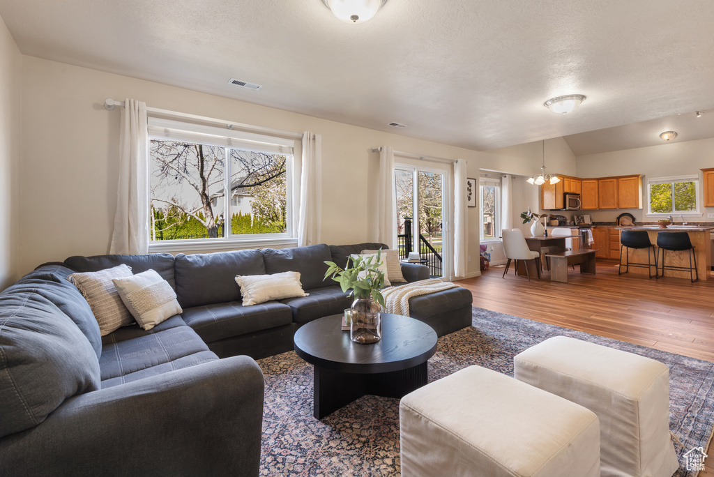 Living area featuring wood finished floors, a wealth of natural light, a notable chandelier, and visible vents