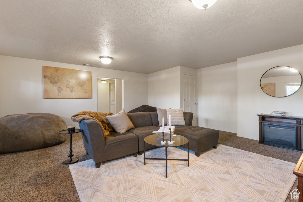 Living room with carpet flooring, a textured ceiling, and a fireplace