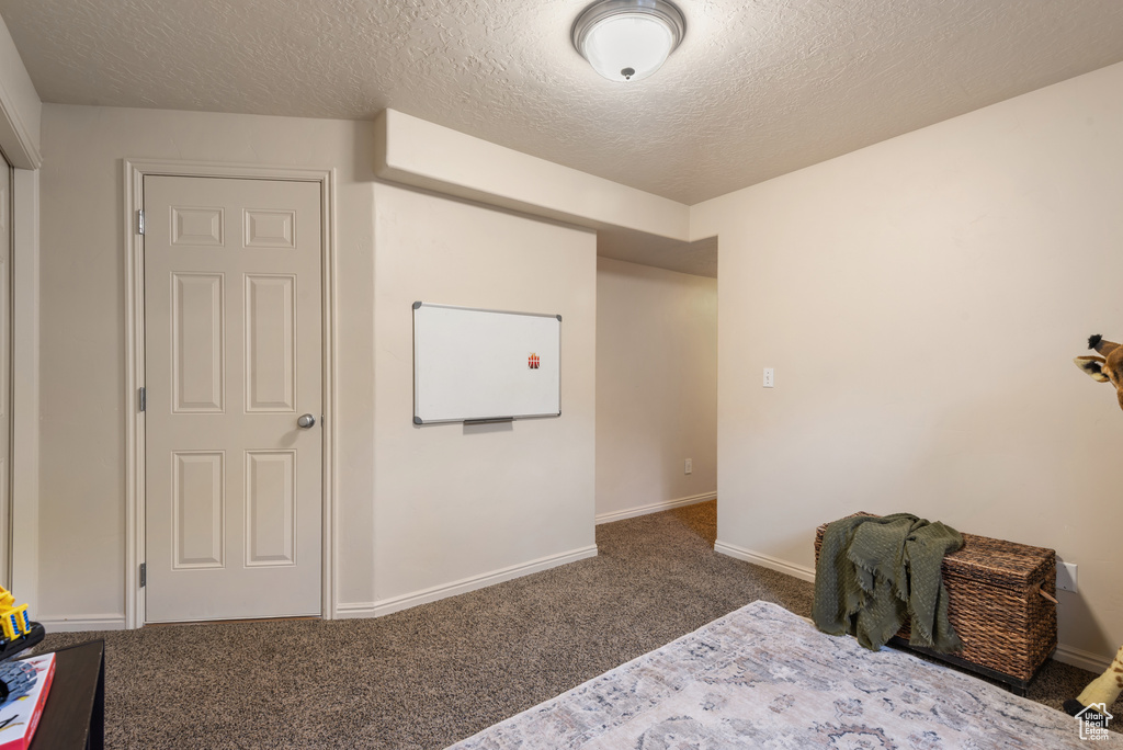 Carpeted bedroom featuring a textured ceiling and baseboards