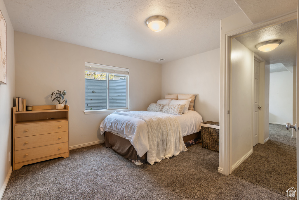 Carpeted bedroom featuring baseboards and a textured ceiling