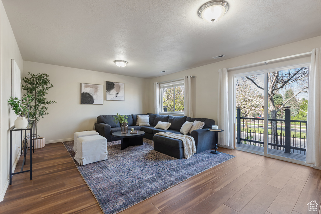 Living room with baseboards, dark wood-style flooring, and a textured ceiling