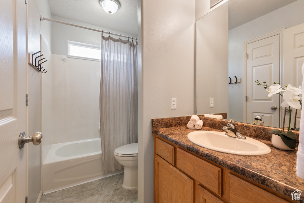 Bathroom with tile patterned flooring, shower / bath combo with shower curtain, toilet, and vanity