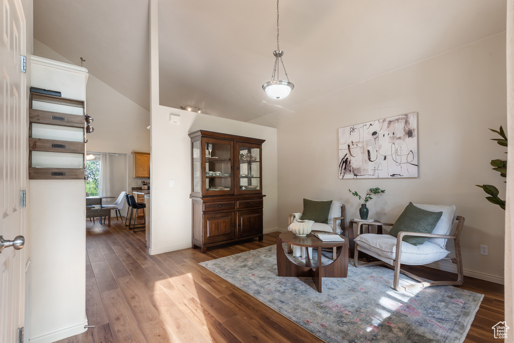 Sitting room with high vaulted ceiling, light wood-style floors, and baseboards