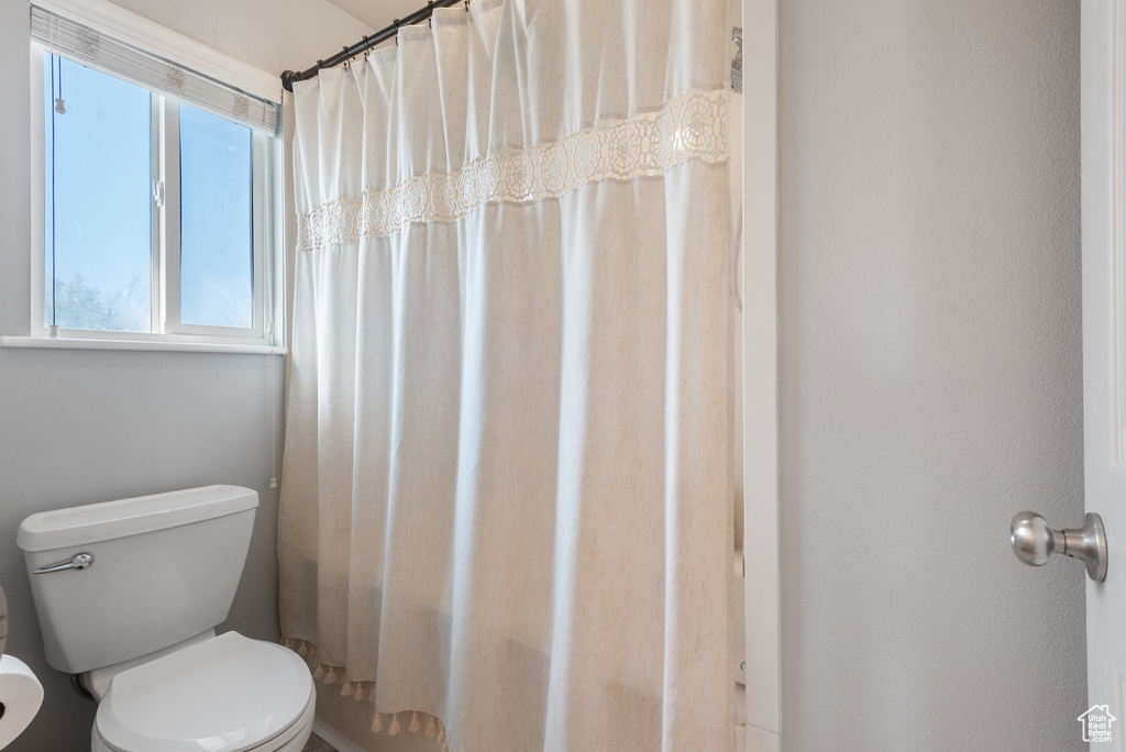 Bathroom with toilet and a shower with shower curtain