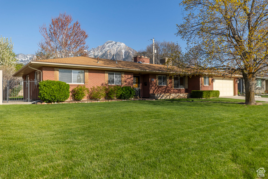 Ranch-style house featuring an attached garage, a mountain view, brick siding, and concrete driveway