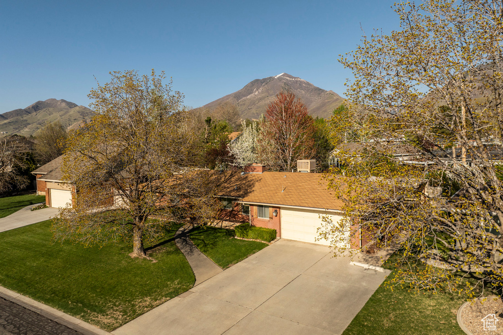 View of front of property with a front lawn, driveway, a mountain view, and a garage