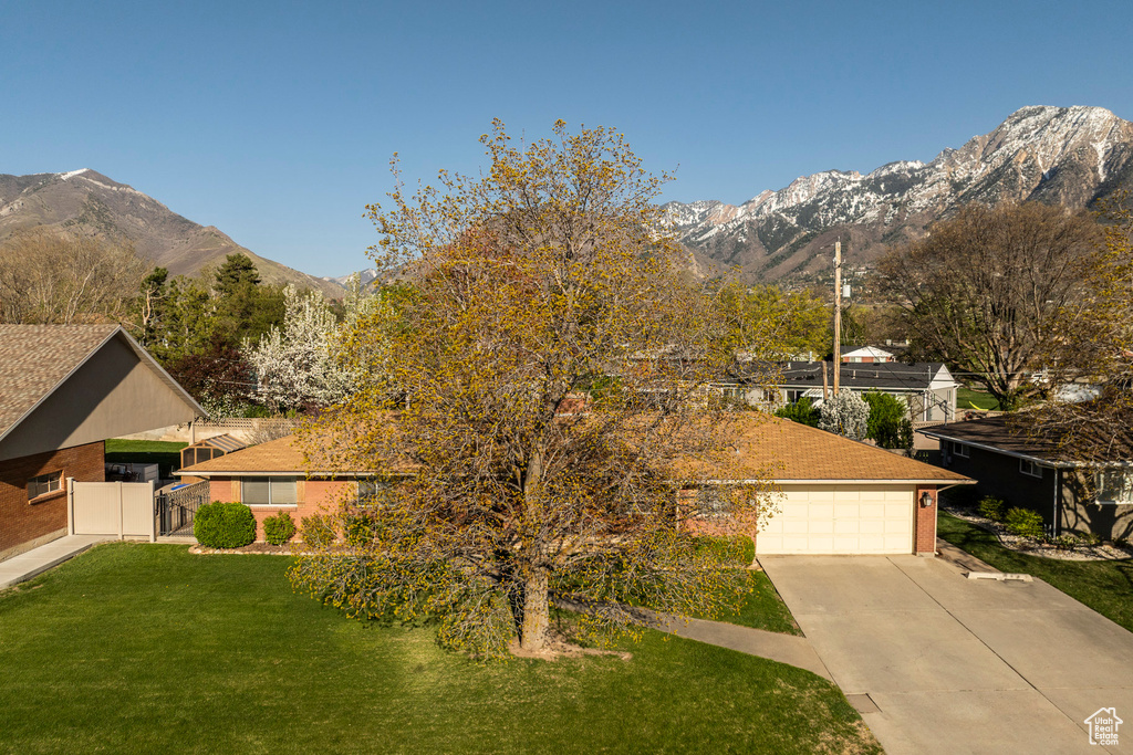 View of front of home with a garage, a mountain view, a front lawn, and concrete driveway