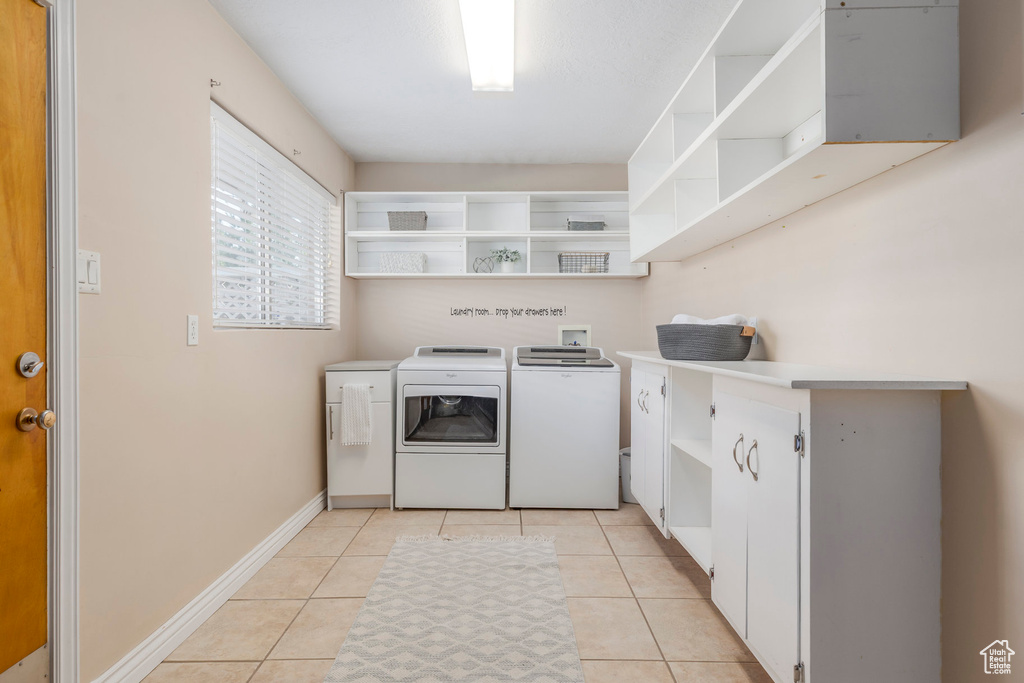 Washroom with independent washer and dryer, light tile patterned floors, and baseboards