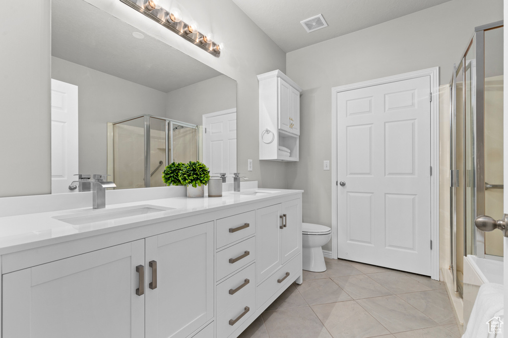 Bathroom featuring visible vents, a sink, double vanity, and a stall shower