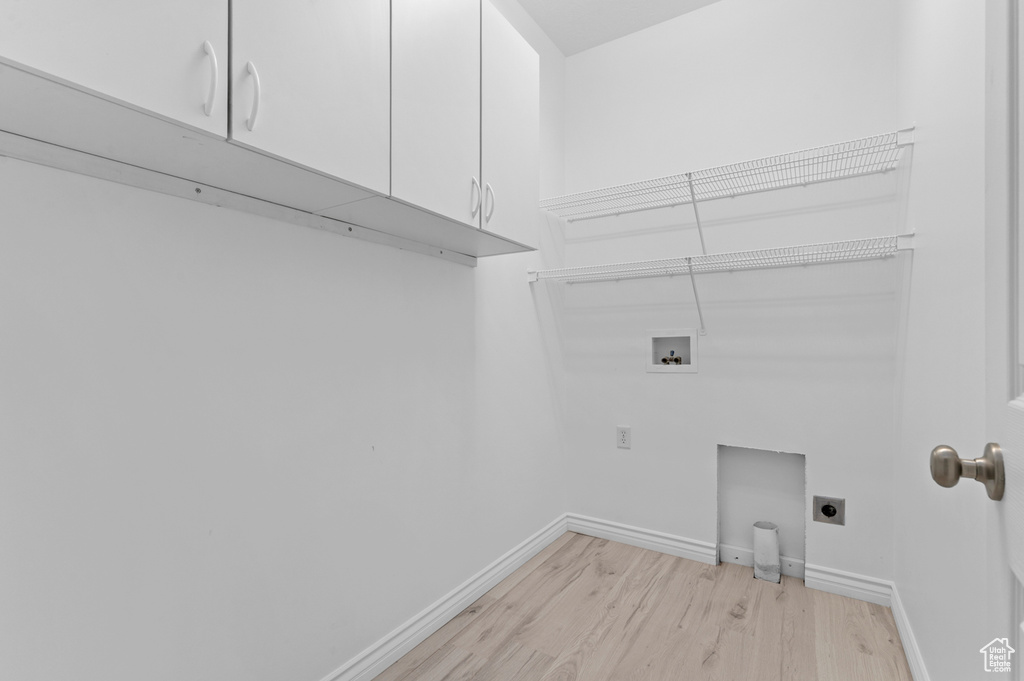 Washroom featuring light wood finished floors, baseboards, hookup for a washing machine, cabinet space, and electric dryer hookup