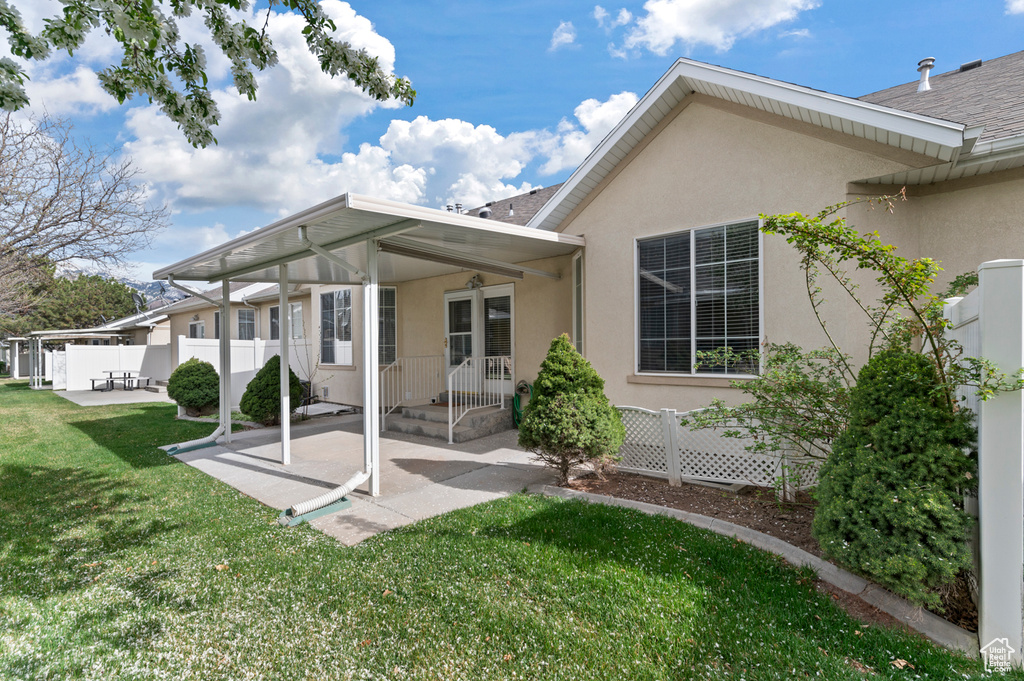 Back of property featuring fence, a patio area, a yard, and stucco siding