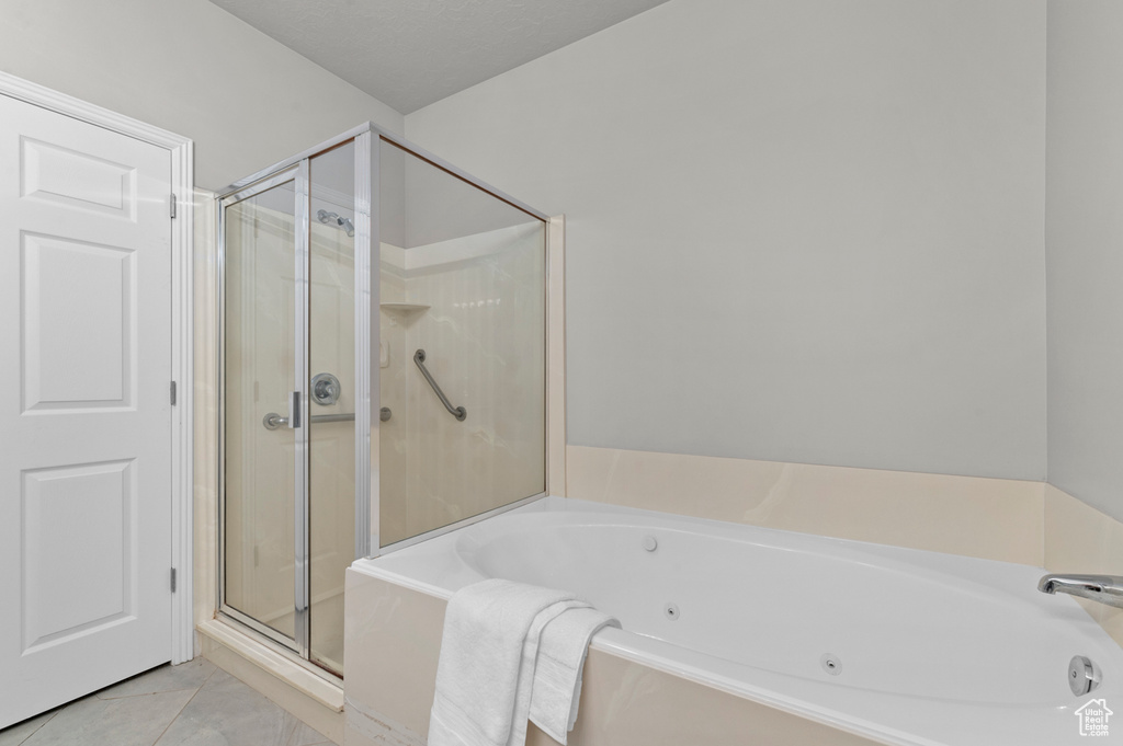 Full bathroom with a whirlpool tub, tile patterned flooring, and a stall shower