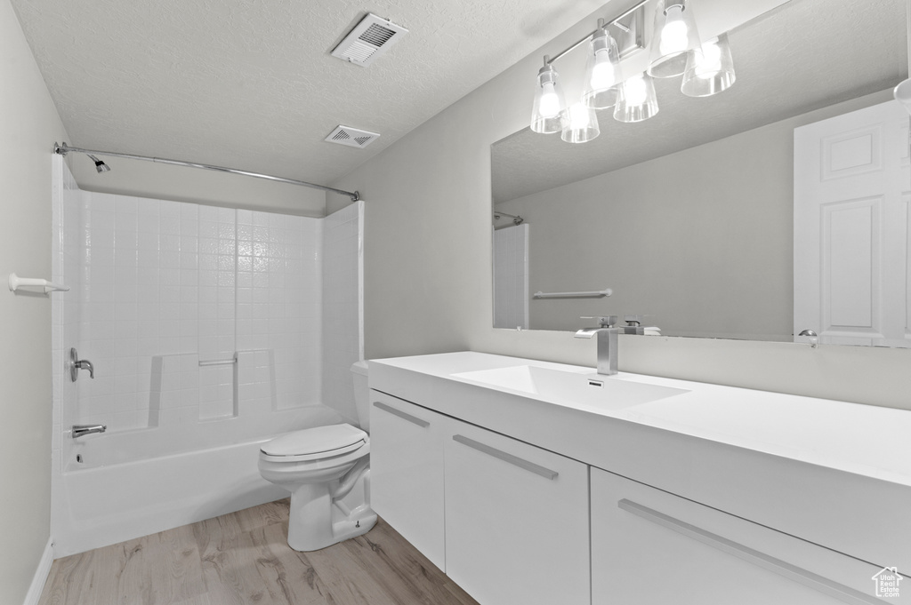 Bathroom with a textured ceiling, wood finished floors, visible vents, and toilet