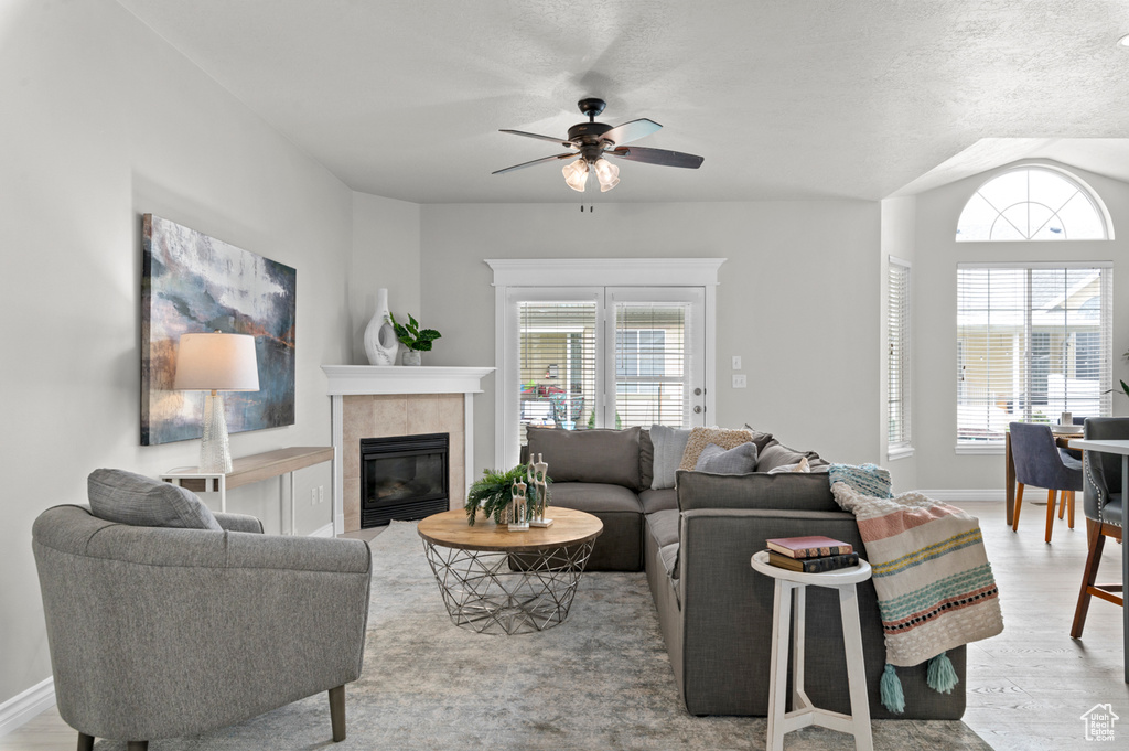 Living area featuring baseboards, a tile fireplace, wood finished floors, and ceiling fan
