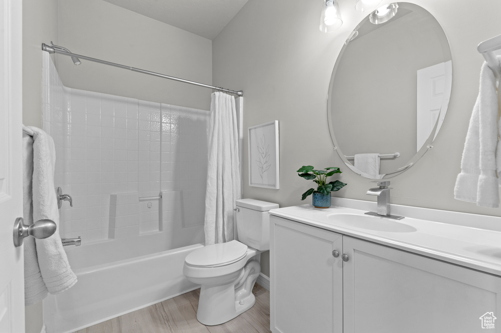 Full bathroom with shower / tub combo, toilet, vanity, and wood finished floors