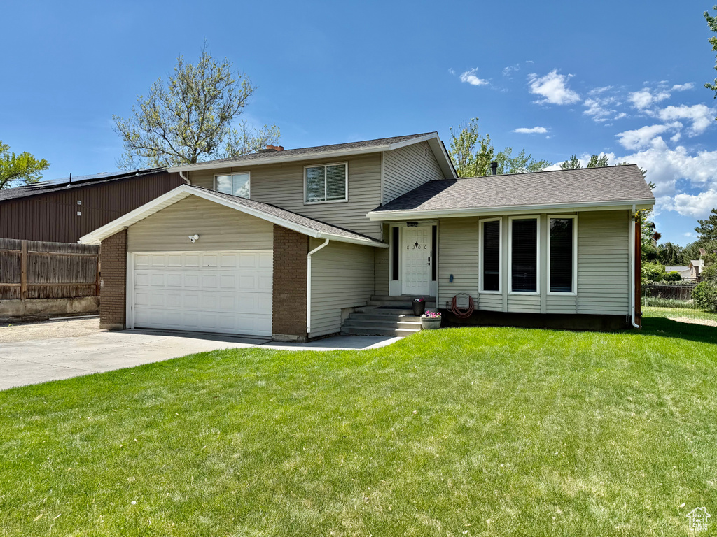 Tri-level home with a garage, concrete driveway, a shingled roof, and brick siding