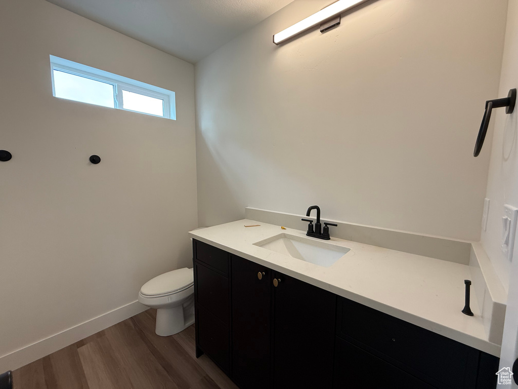 Bathroom with toilet, wood finished floors, vanity, and baseboards