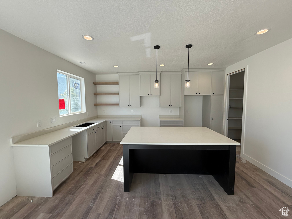 Kitchen with a center island, dark wood-style flooring, recessed lighting, open shelves, and pendant lighting