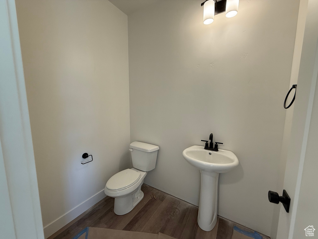 Half bath with wood finished floors, toilet, and a sink