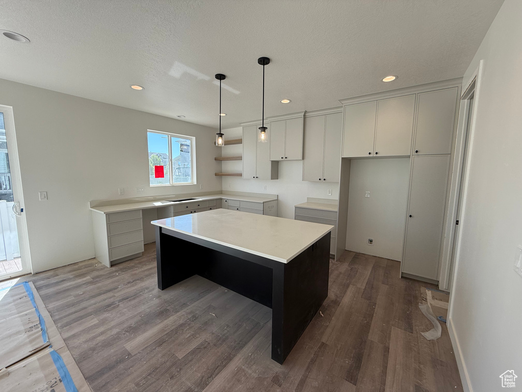 Kitchen featuring a kitchen island, wood finished floors, recessed lighting, hanging light fixtures, and light countertops