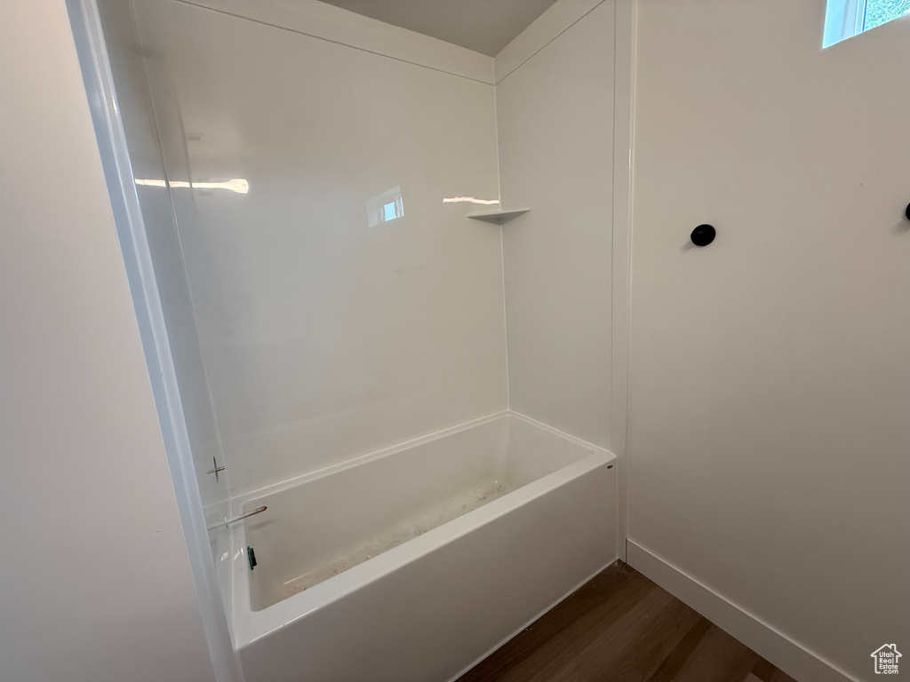 Full bathroom featuring wood finished floors, baseboards, and shower / washtub combination